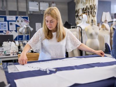 A woman measuring fabric in a costume workshop